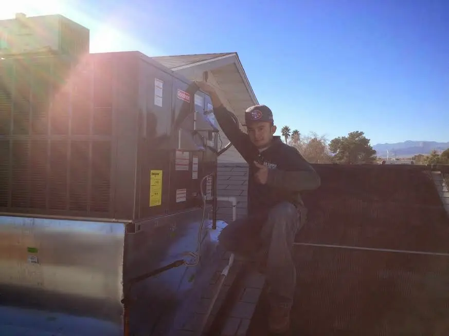HVAC technician performing AC Tune-Up on a rooftop unit in Enfield